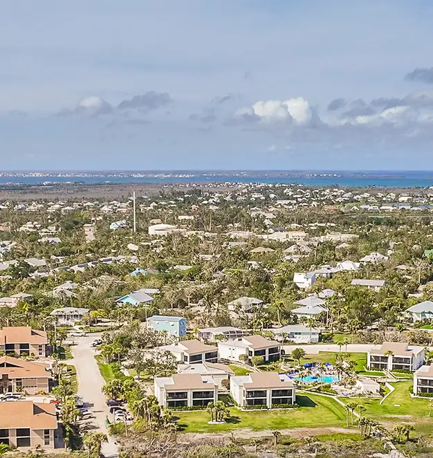 Aerial view of a coastal residential community with clusters of single-family homes and apartment buildings—showcasing the reach and neighborhood-scale impact of ArmCoa’s construction projects.