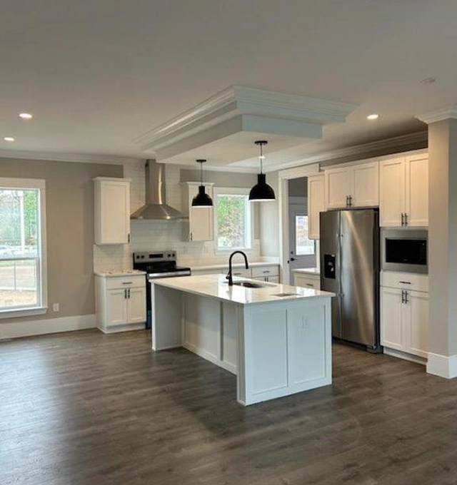 Updated rental property kitchen with center island, stainless steel appliances, and pendant lighting