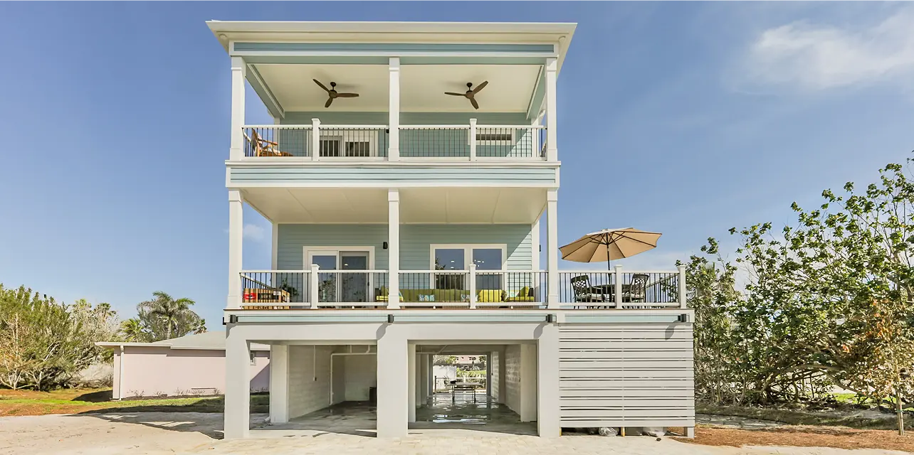 Elevated blue spec home built by ArmCoa, showcasing precision construction, hurricane-ready foundation, and livable outdoor space.